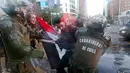Polisi anti huru hara mengamankan seorang pengunjuk rasa saat terjadi aksi di luar kedutaan AS di Santiago, Chili (14/4). Para demonstran melakukan aksi menentang serangan AS dan sekutunya ke Suriah. (AP / Esteban Felix)