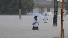 Orang-orang menyeberang jalan akibat hujan lebat di Kurume, Prefektur Fukuoka, Jepang selatan Senin, 10 Juli 2023. (Kyodo News via AP)