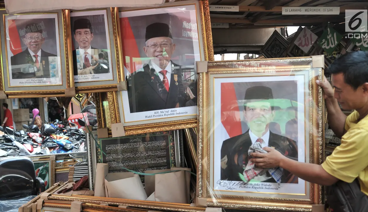 Pedagang merapikan foto Presiden-Wapres 2019-2024, Joko Widodo-KH Ma'ruf Amin di salah satu toko di Pasar Baru, Jakarta, Senin (26/8/2019). Meski belum resmi dilantik, foto Presiden dan Wakil Presiden Terpilih Joko Widodo-KH Ma'ruf Amin telah beredar di pasaran. (merdeka.com/Iqbal S. Nugroho)