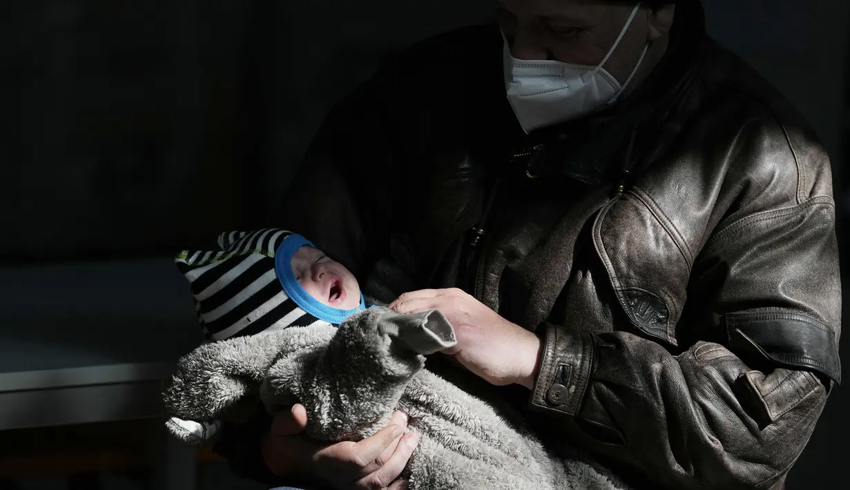 Seorang pengungsi dari Lviv, Ukraina, menggendong bayi setibanya di markas Palang Merah di Roma, Italia pada Selasa (22/3/2022). Konvoi kendaraan Palang Merah yang membawa 80 orang, sebagian besar orang tua dan sakit tiba pada Selasa di Roma. (AP Photo/Alessandra Tarantino)