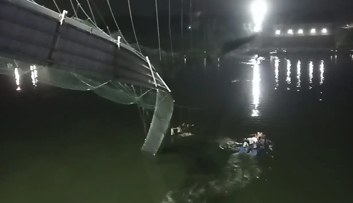 Tim penyelamat di kapal mencari di sungai Machchu di sebelah jembatan kabel yang runtuh di distrik Morbi, negara bagian Gujarat barat, India, Minggu, 30 Oktober 2022. Puluhan dikhawatirkan tewas dan beberapa terluka dalam kecelakaan itu.