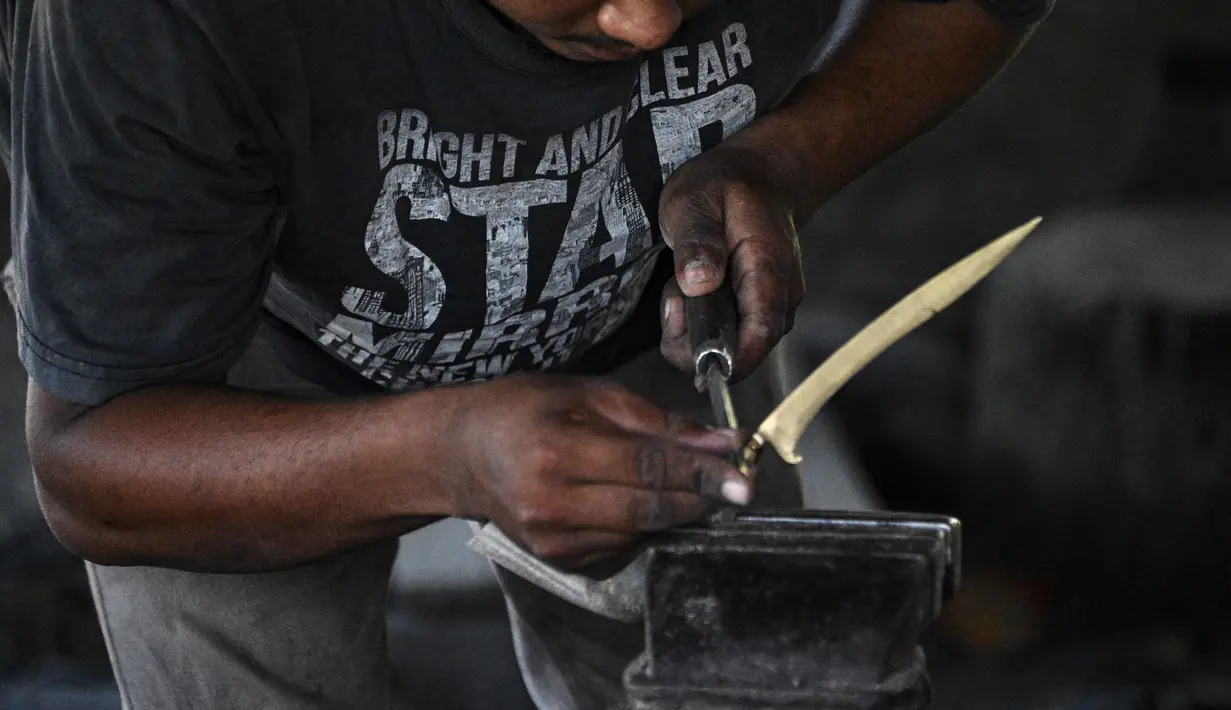 Seorang pandai besi membuat keris tradisional yang dikenal sebagai 'rencong' di sebuah bengkel di Sibreh, provinsi Aceh (5/10/2021). Rencong merupakan senjata khas Suku Aceh. (AFP/Chaideer Mahyuddin)