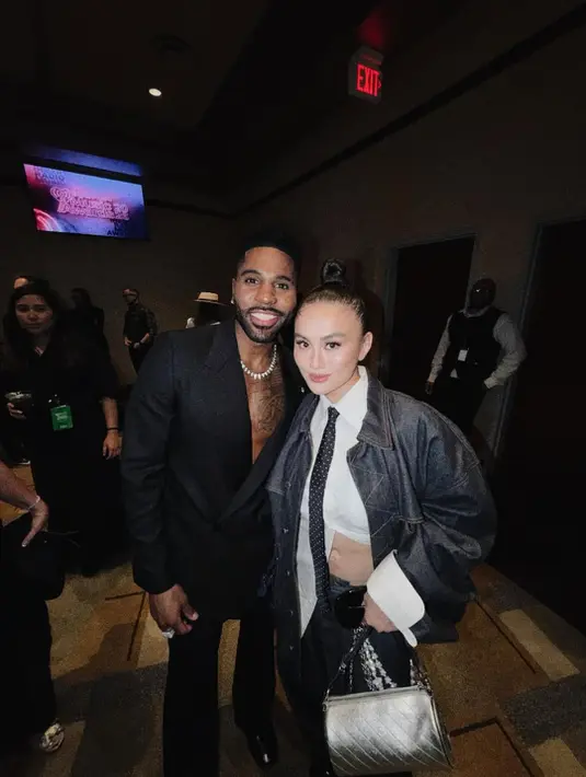 Dengan aksi detail silver yang ditampilkan pada tas dan juga aksen rantai, pada celana, semburat gaya Y2K [Foto: Instagram/ Agnez Mo]