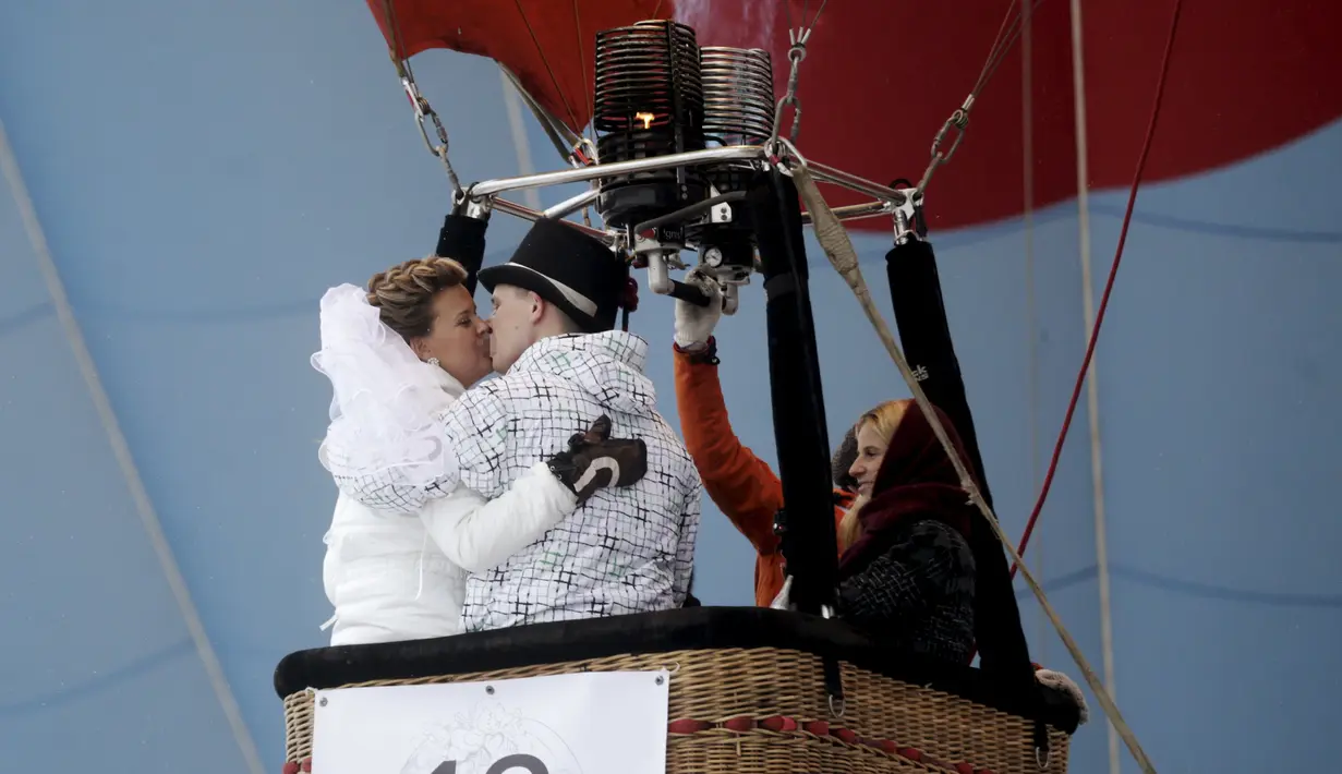 Pengantin baru terlihat mesra saat berada di balon udara saat mengikuti Festival Love Cup 2016 di Jekabpils, Latvia (14/2). Sebanyak 50 pasangan pengantin dibagi dalam 27 balon udara terbang bersama mengikat janji cinta mereka. (REUTERS/Ints Kalnins)