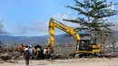 Warga menyaksikan proses evakuasi Nanang Kosim (20) menggunakan alat berat, yang diduga masih tertimbun di dalam tanah pascagempa dan tsunami Palu di Pantai Talise, Sulawesi Tengah, Senin (8/10). (Liputan6.com/Fery Pradolo)
