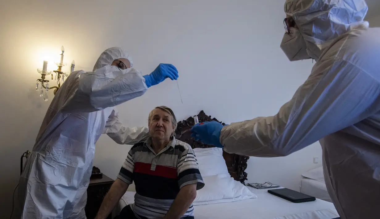 Petugas kesehatan dengan APD merawat tunawisma pasien virus corona di sebuah kamar hotel di Praha, Senin (8/3/2021). Hotel yang dulunya menjadi tujuan wisatawan internasional itu kini membuka pintunya bagi para tunawisma yang sakit terpapar Covid-19 atau perlu karantina. (MICHAL CIZEK/AFP)