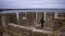 Seorang pria memegang kucing mengunjungi benteng Akkerman di sungai Dnester, di wilayah Odessa, Ukraina (19/2/2022). Benteng abad pertengahan "Akkerman", di tepi muara Dniester dianggap sebagai salah satu kastil terbesar dan terpelihara dengan baik di Ukraina. (AP Photo/Emilio Morenatti)