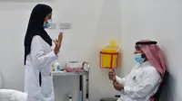 Seorang perawat berbicara kepada seorang pria sebelum memberikan vaksin Covid-19 di pusat vaksinasi yang diawasi Kementerian Kesehatan Arab Saudi di Riyadh, Arab Saudi, Kamis (17/12/2020). Berdasarkan informasi, proses vaksinasi di Arab Saudi akan dilakukan dalam tiga tahap.  (AFP/Fayez Nureldine)