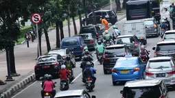 Pengendara motor melintas di sisi mobil parkir di jalur khusus motor di sekitar Jalan Medan Merdeka Barat, Jakarta, Kamis (1/3). Jalur yang seharusnya digunakan untuk pengendara motor tersebut hingga kini belum steril. (Liputan6.com/Helmi Fithriansyah)