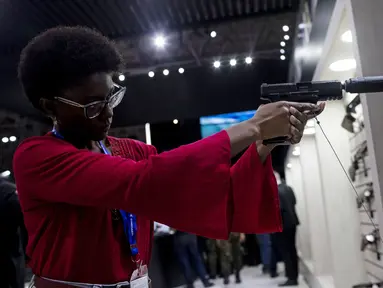 Seorang wanita memegang pistol dengan peredam di Pameran Internasional Pertahanan dan Keamanan LAAD di Rio de Janeiro, Brasil, Selasa, 11 April 2023. (AP Photo/Bruna Prado)