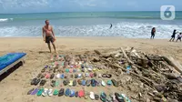Wisatawan asal Belanda menata sampah sandal dan sepatu yang dia kumpulkan dari Pantai Kuta. (merdeka.com/Arie Basuki)