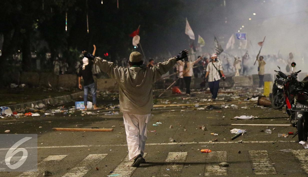 Seorang pendemo berusaha menghalangi kawannya menyerang polisi saat bentrok di Jakarta, Jumat (4/11). Diduga bentrok terjadi saat massa HMI menyerang polisi dan polisi membalasnya dengan melempar gas air mata. (Liputan6.com/Gempur M Surya)