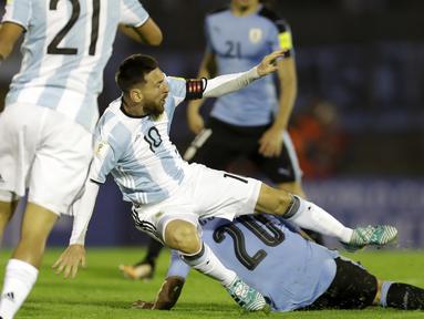 Pemain Argentina, Lionel Messi terjatuh saat berebut bola dengan pemain Uruguay, Alvaro Gonzalez pada laga kualifikasi Piala Dunia 2018 di Montevideo, Uruguay, (31/8/2017). Argentina bermain imbang 0-0. (AP/Natacha Pisarenko)