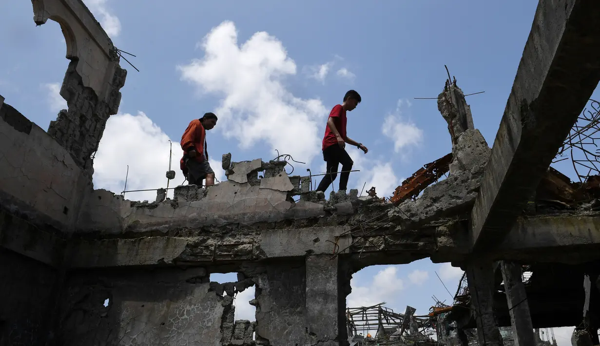Anak-anak berjalan di beton bangunan yang rusak di Kota Marawi, Mindanao, Filipina, Minggu (1/4). Pihak berwenang mengizinkan warga Marawi pulang setelah berhasil membasmi ISIS dari kawasan tersebut. (TED ALJIBE/AFP)