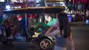 Foto pada 11 Oktober 2018 memperlihatkan turis asing menaiki tuk-tuk melintasi Nana Red Light Distrik di Bangkok, Thailand. Kawasan tersebut merupakan tempat lokalisasi hiburan malam paling tersohor di Bangkok. (Romeo GACAD / AFP)