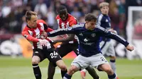 Pemain Brentford, Mikkel Damsgaard, mencoba merebut bola dari gelandang Manchester United (MU), Manuel Ugarte, dalam laga pekan ke-35 Premier League di Gtech Community Stadium, London, Minggu (4/5/2025) malam WIB. (John Walton/PA via AP)