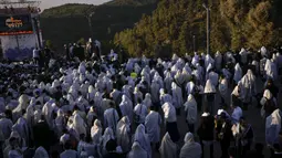 Orang-orang Yahudi Ultra Ortodoks yang ditutupi selendang berdoa saat perayaan liburan Lag BaOmer di situs makam tradisional Rabbi Shimon Bar Yochai di Gunung Meron, Israel, Kamis (19/5/2022). Orang Israel menyalakan api unggun selama perayaan Lag BaOmer untuk memperingati berakhirnya wabah yang dikatakan telah memusnahkan orang Yahudi di zaman Romawi. (AP Photo/Ariel Schalit)