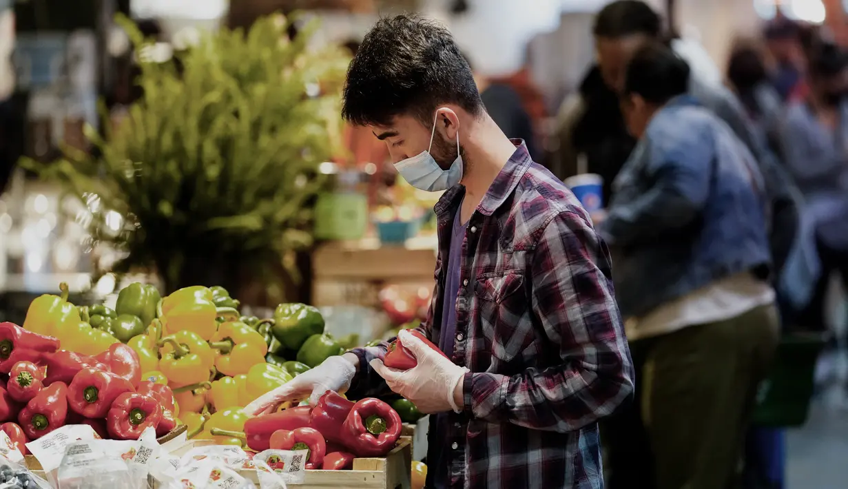 <p>Serang pedagang yang mengenakan masker menata dagangannya di Reading Terminal Market di Philadelphia, Jumat (22/4/2022). Kota itu meninggalkan mandat masker dalam ruangan pada hari Jumat, hanya beberapa hari setelah menjadi kota metropolitan AS pertama yang menerapkan kembali wajib masker sebagai tanggoapan atas peningkatan kasus COVID-19 dan rawat inap. (AP Photo/Matt Rourke)</p>