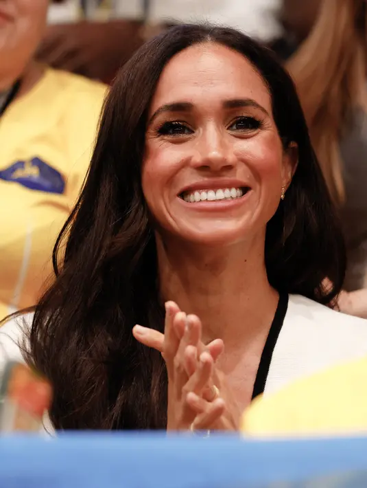 <p>Duchess of Sussex itu akhirnya kembali muncul ke muka publik bersama sang suami, Pangeran Harry. (Odd ANDERSEN / AFP)</p>