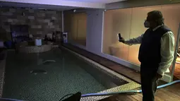 Pemilik Kenton Palace Hotel, menyalakan lampu kolam renang tertutup di Buenos Aires, Argentina pada pada 17 Juni 2021. Pembatasan akibat pandemi corona Covid-19 telah menyebabkan penurunan jumlah wisatawan selama setahun di Argentina. (RONALDO SCHEMIDT / AFP)