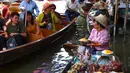 Pedagang menawarkan mangga kepada wisatawan yang sedang naik kapal di pasar terapung Damnoen Saduak, Bangkok, Thailand, Jumat (21/6/2019). Selain buah-buahan, berbagai jenis makanan dan barang juga dijual di pasar terapung Damnoen Saduak. (TANG CHHIN Sothy/AFP)