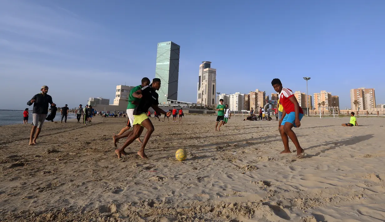 Orang-orang bermain bola di pantai sembari menunggu waktu berbuka puasa selama bulan suci Ramadan, meskipun lockdown karena pandemi COVID-19, di ibu kota Tripoli, Libya pada Jumat (8/5/2020). (Photo by Mahmud TURKIA / AFP)