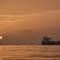 Matahari terbit di balik kapal tanker yang berlabuh di Selat Hormuz di lepas pantai Pulau Qeshm, Iran, Sabtu, 18 April 2026. (AP Photo/Asghar Besharati)