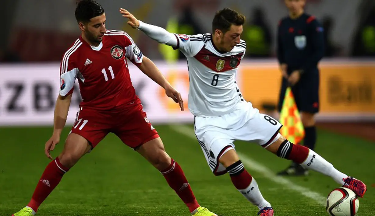 Gelandang Jerman, Mesut Ozil (kanan) mengontrol bola di samping pemain Georgia Giorgi Chanturia saat kualifikasi Piala Eropa 2016 di Locomotiv Stadium, Minggu (29/3/2015). Jerman menang 2-0 atas Georgia. (AFP PHOTO/Patrik Stollarz)