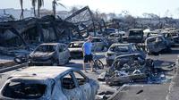 Seorang pria berjalan melewati reruntuhan kebakaran hutan di Lahaina, Hawaii, Amerika Serikat, Jumat (11/8/2023). (AP Photo/Rick Bowmer)
