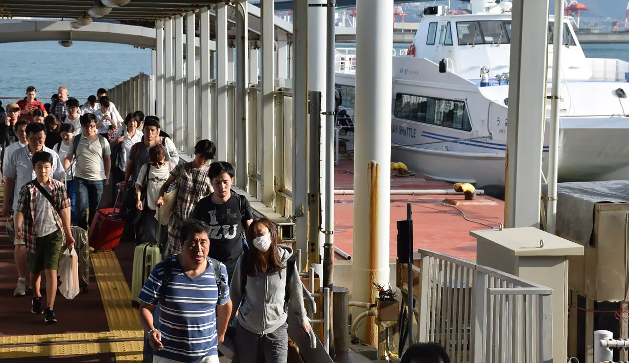 Penumpang yang terdampar semalam di Bandara Internasional Kansai tiba dengan menggunakan kapal di pelabuhan Kobe, Rabu (5/9). Topan jebi yang menerjang Jepang telah merusak jembatan penghubung  Bandara Kansai dengan daratan utama Osaka. (AFP/JIJI PRESS)