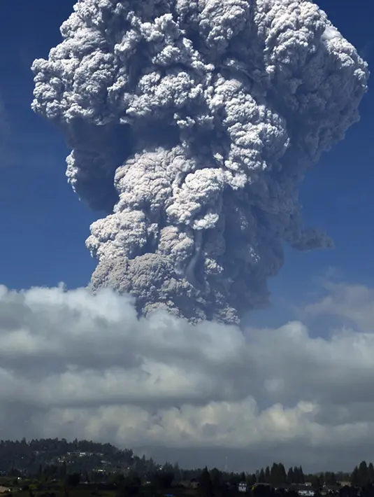 Gunung Sinabung yang mengeluarkan abu tebal terlihat dari kota Berastagi di Sumatera Utara (19/2). Gunung Sinabung kembali menyemburkan abu vulkanik tebal dengan tinggi kolom 5.000 meter. (AFP Photo/Anto Sembiring)