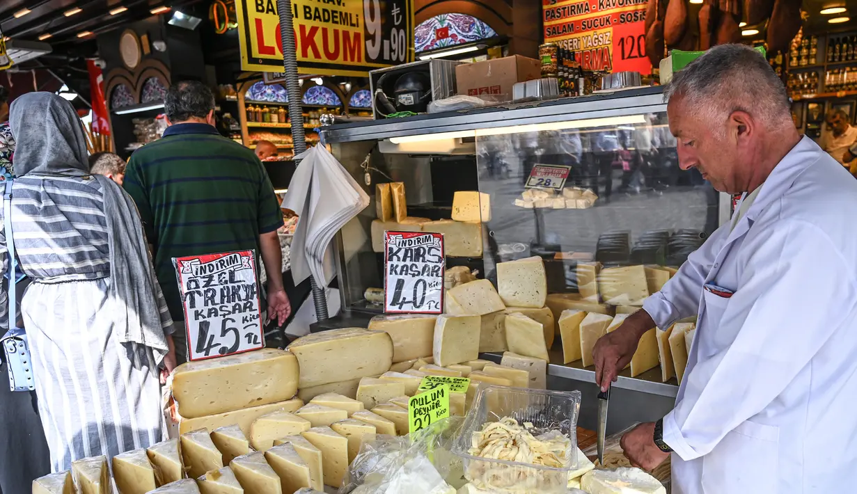 Seorang pedagang memotong keju di Spice Bazaar yang bersejarah di distrik Eminonu di Istanbul, Turki (13/7/2019). Spice Bazaar dipenuhi oleh pengunjung selama bulan ramadan. (AFP Photo/Ozam Kose)