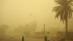 Orang-orang berjalan di jalan di ibu kota Irak, Baghdad, saat debu tebal akibat badai pasir menyelimuti kota itu, pada Senin (23/5/2022). Irak menutup bandara dan gedung-gedung publik saat badai pasir -- yang kesembilan sejak pertengahan April -- melanda negara itu, kata pihak berwenang. (Sabah ARAR / AFP)