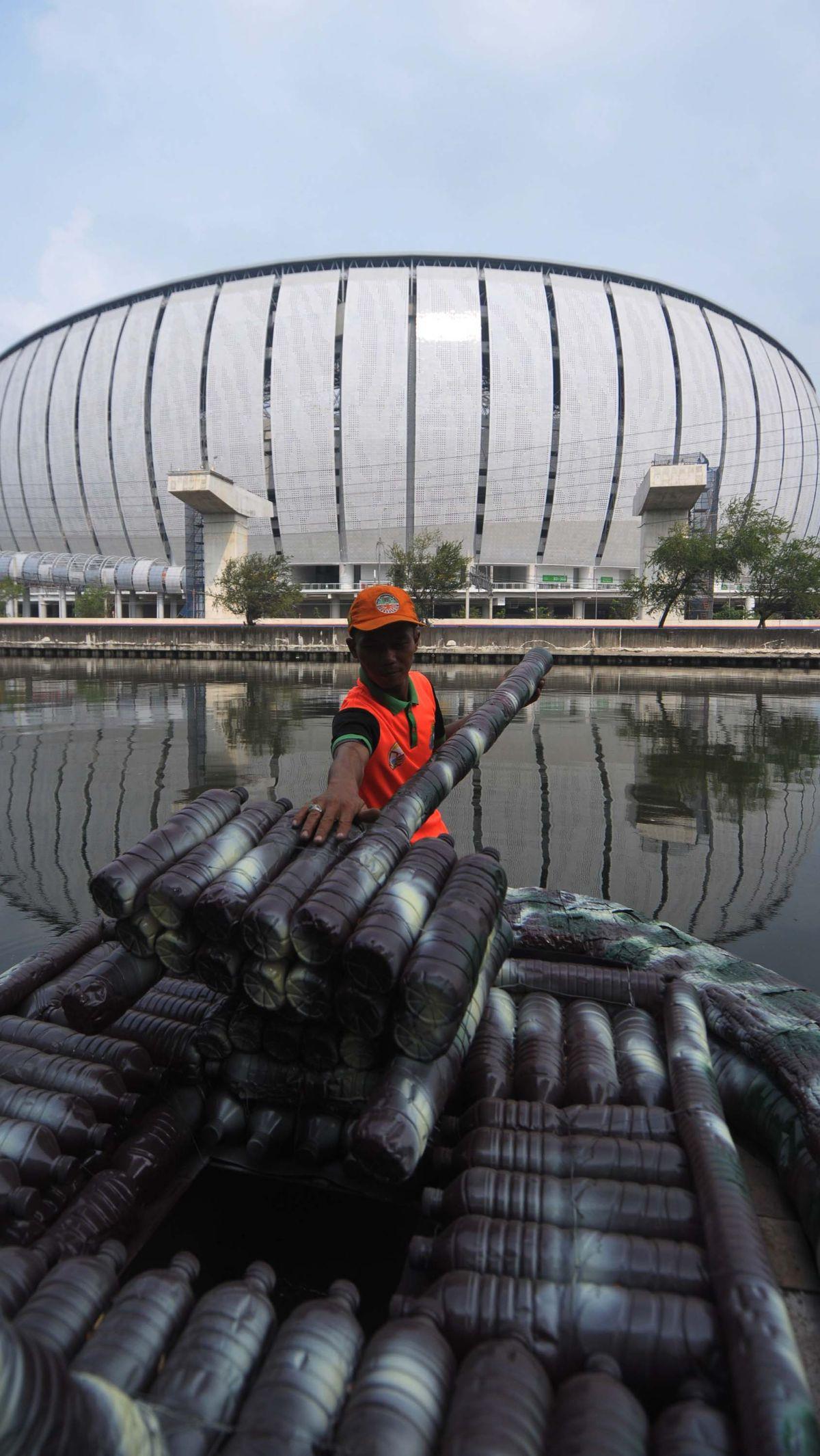 Petugas UPS Badan Air Dinas Lingkungan Hidup DKI Jakarta mengambil sampah menggunakan perahu yang terbuat dari sampah botol plastik di aliran Kali Ancol, Jalan Martadinata, Jakarta Utara, Rabu (22/5/2024).&nbsp;Foto: Merdeka.com/Imam Buhori