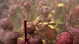 Sejumlah pria India bernyanyi dan bermain musik dengan tubuh berlumuran warna saat mengikuti festival Holi di desa Nandgaon di negara bagian Uttar Pradesh, India (7/3). (AFP)