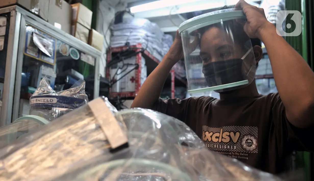 Pedagang mencoba alat pelindung wajah atau face shield di salah satu kios Pasar Pramuka, Jakarta, Rabu (3/6/2020). Jelang pemberlakuan new normal, penjualan face shield meningkat dalam beberapa hari terakhir. (merdeka.com/Iqbal S. Nugroho)