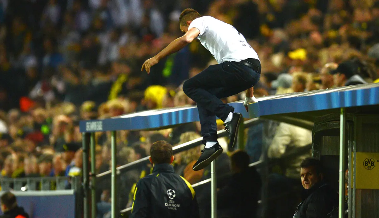 Seorang penonton nekat melompati atap bangku pemain cadangan saat laga antara Borussia Dortmund vs Real Madrid berlangsung pada penyisihan Grup D UEFA Champions League 2012 lalu. ( AFP/Patrik Stollarz )