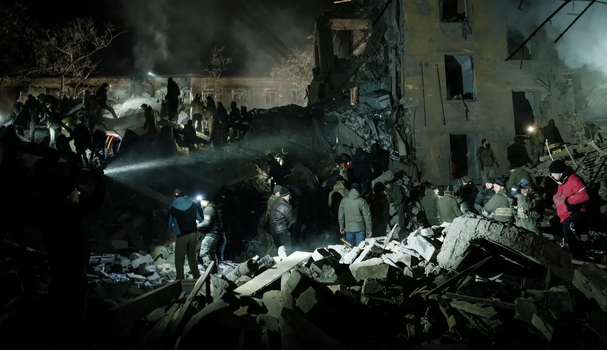 <p>Tim penyelamat memindahkan puing-puing untuk mencari korban selamat di gedung apartemen yang hancur terkena roket pada malam hari di pusat kota Kramatorsk, Ukraina timur, pada Rabu (1/2/2023). Sedikitnya 3 orang tewas dan 21 luka-luka dalam serangan itu. (Yasuyoshi CHIBA / AFP)</p>