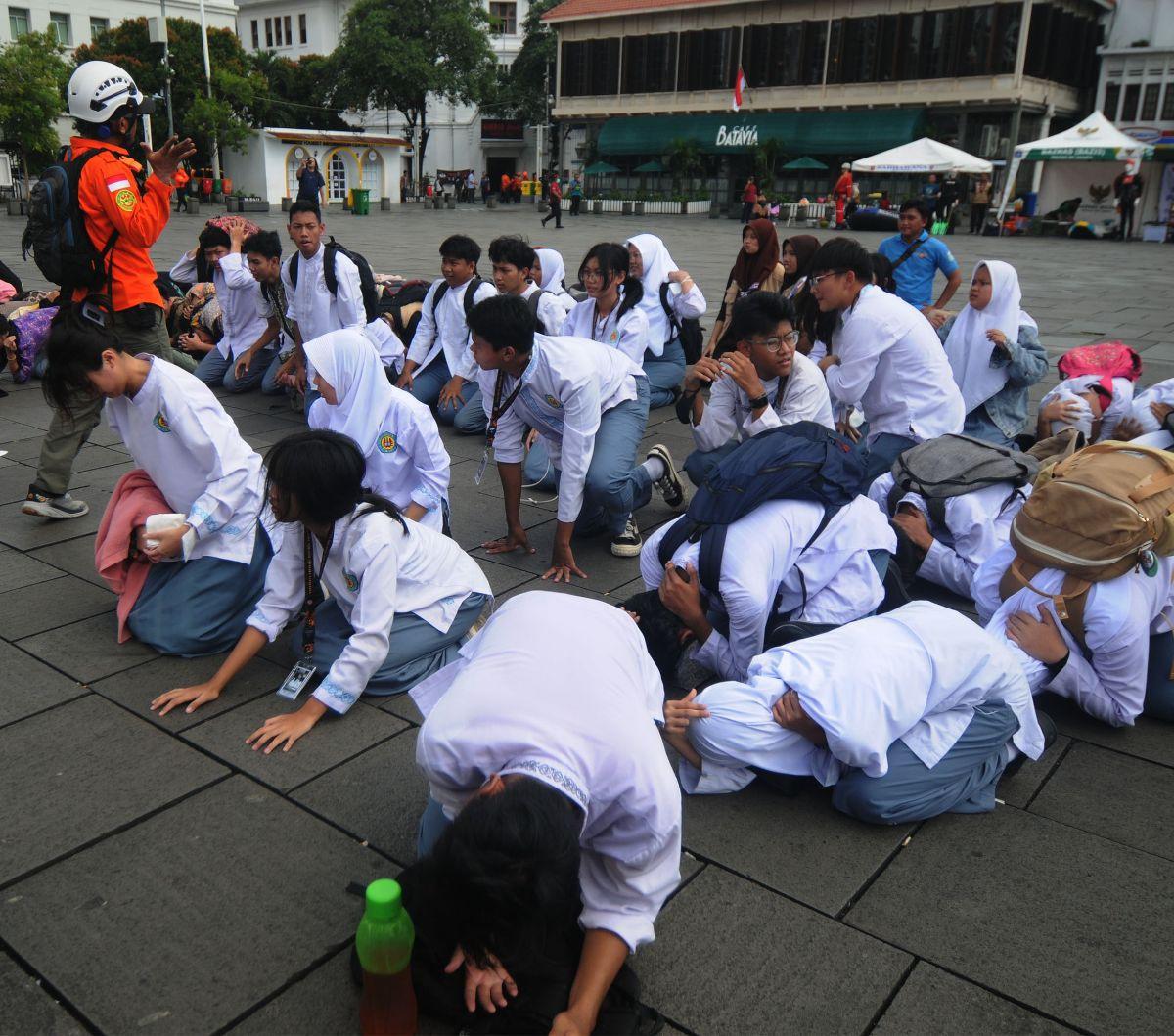 Sejumlah siswa merunduk ketika sirine gempa meraung-raung dalam simulasi yang digelar pada Hari Kesiapsiagaan Bencana 2024 di kawasan Kota Tua, Jakarta, Jumat (26/4/2024).&nbsp;Relawan yang tergabung dalam Tim Penanggulangan Bencana Indonesia menggelar pe