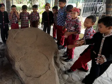 Murid SD melihat prasasti telapak kaki gajah di Prasasti Kebun Kopi, Ciaruteun Ilir, Bogor, Jawa Barat, Rabu (15/8). Prasasti ini peninggalan budaya Kerajaan Tarumanegara yang berdiri pada abad 4 hingga 7 masehi di Pasundan. (Merdeka.com/Arie Basuki)