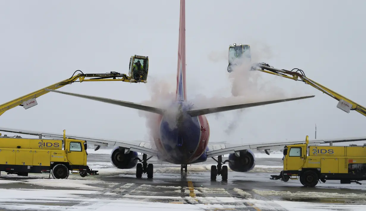 Layanan Deicing Terpadu membersihkan pesawat Southwest Airlines sebelum lepas landas di Bandara Internasional Salt Lake City di Salt Lake City, Utah (22/2/2023). Cuaca musim dingin yang brutal menghantam AS bagian utara pada hari Rabu dengan salju yang "putih", hembusan angin yang berbahaya dan dingin yang menggigit, menutup jalan raya, menutup sekolah dan bisnis, serta mendorong peringatan yang mengerikan bagi orang-orang untuk tinggal di rumah. (AP Photo/ Rick Bowmer)
