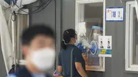 Pekerja medis yang mengenakan alat pelindung di sebuah bilik mengambil sampel wanita selama pengujian COVID-19 di tempat pengujian virus corona di Seoul, Korea Selatan, Rabu (1/9/2021). Korea Selatan pada hari Rabu melaporkan lebih dari 2.000 kasus virus corona baru. (AP Photo/Ahn Young-joon)