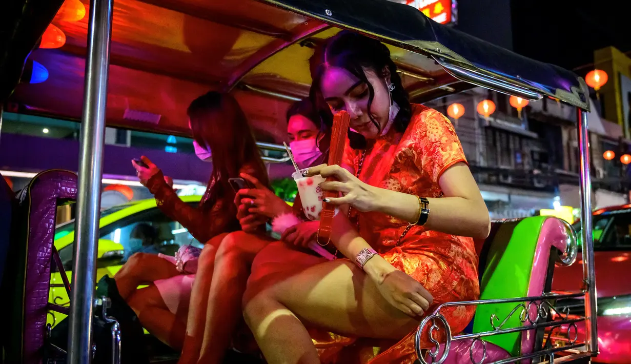 Wanita berbusana China menaiki tuk-tuk tradisional di jalan yang didekorasi untuk menyambut Tahun Baru Imlek di Chinatown Bangkok (9/2/2021). Berbagai acara dibatalkan dan ditunda seperti konser Green Day dan Bangkok Design Week 2021. (AFP/ Mladen Antonov)