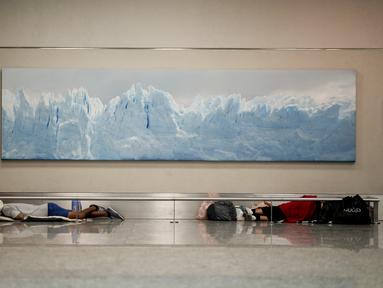 Para tunawisma tidur di bawah foto Gletser Perito Moreno di bandara internasional Jorge Newbery, umumnya dikenal sebagai Aeroparque, di Buenos Aires, Argentina, Kamis, 6 April 2023. (AP Photo/Natacha Pisarenko)
