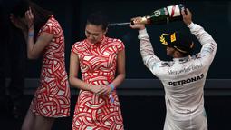 Lewis Hamilton menyemprotkan sampanye ke arah gadis podium.