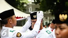 Anggota Paskibraka 2016 merapikan peci rekannya saat bersiap melaksanakan gladi bersih Upacara HUT ke-71 Kemerdekaan RI di Istana Merdeka, Jakarta, Senin (15/8). (Liputan6.com/Faizal Fanani)