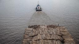 Sebuah kapal tongkang berisi kayu gelondongan ditarik di sepanjang Sungai Mahakam melewati Kota Samarinda, Kalimantan Timur, 4 November 2021. (ADITYA AJI/AFP)