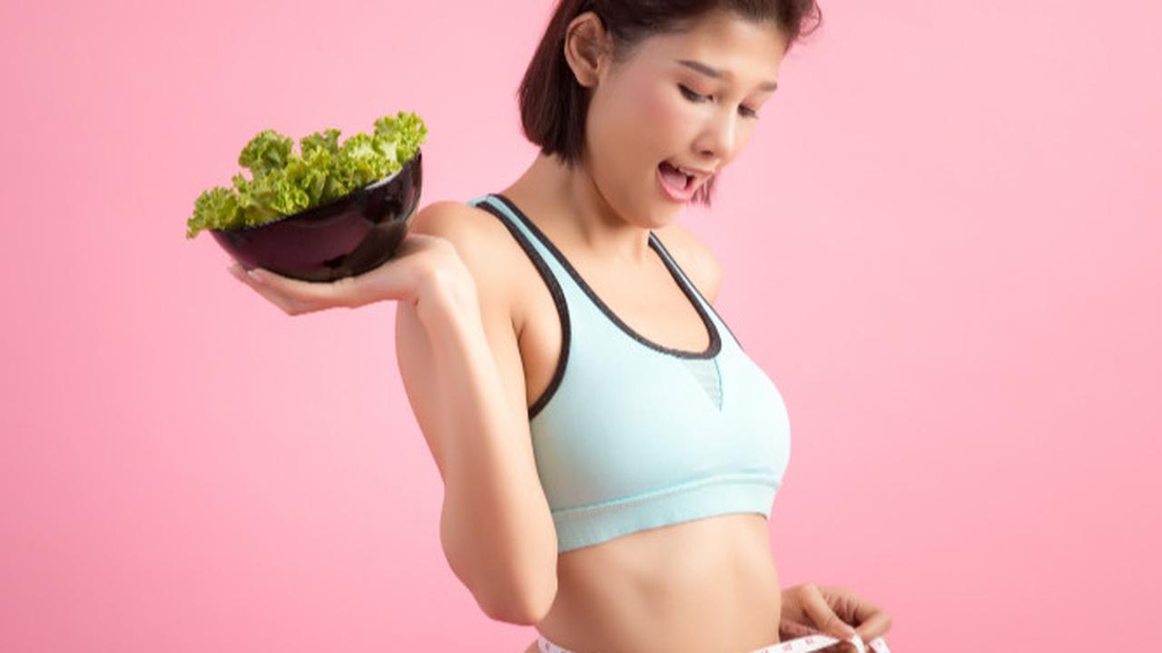 Wanita yang Mengukur Badannya dan Membawa Makanan Dietnya