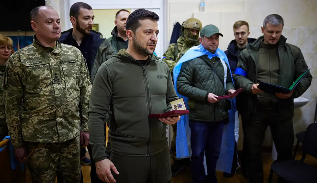 Dalam foto yang disediakan oleh Kantor Pers Kepresidenan Ukraina pada 13 Maret 2022, Presiden Ukraina Volodymyr Zelenskyy (tengah) bersiap untuk memberikan medali negara kepada tentara yang terluka saat kunjungannya ke sebuah rumah sakit di Kiev, Ukraina. (Ukrainian Presidential Press Office via AP)