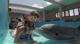 Seorang anak menerima ciuman dari lumba-lumba bernama Xinana selama sesi terapi di National Aquarium, Kuba, Senin (26/5/14). (AFP PHOTO/Adalberto ROQUE)